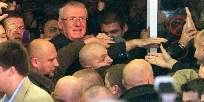 Serbian nationalist Vojislav Seselj (L) arrives at Nikola Tesla Airport in Belgrade on November 12, 2014, after spending 12 years on trial at the Hague Criminal Tribunal for the former Yugoslavia. Ailing Serb leader Vojislav Seselj has been released from the UN Yugoslav war crimes tribunal and has left the Netherlands en route for Serbia, the court said on November 12. The International Criminal Tribunal for the former Yugoslavia (ICTY) last week ordered his release so he could return home for cancer treatment as he awaits a verdict on alleged war crimes during the Balkan wars. AFP PHOTO / ANDREJ ISAKOVIC