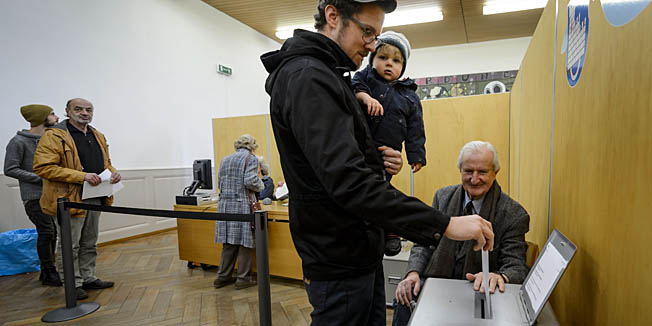 A man casts his ballot on November 30, 2014 in the old town of Fribourg. The Swiss voted early Sunday in three national referendums, including one calling for dramatic immigration cuts in the name of saving the environment, in polling open for just two hours. Most voters, however, had already cast their ballots by mail, and initial results were expected to be available shortly after polling stations closed at noon.  AFP PHOTO / FABRICE COFFRINI