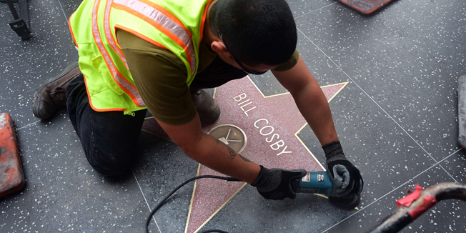 A worker cleans Bill Cosby's Star on the Hollywood Walk of Fame on December 5, 2014 in Hollywood, California after it was reportedly vandalized the night before with the word 