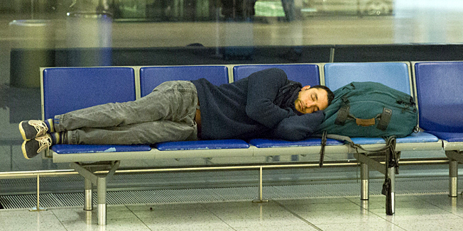 A man rests on seats in the departures lounge in the north terminal at Gatwick Airport, south of London on December 12, 2014. A computer failure at an air traffic control centre sparked travel chaos in Britain on Friday as the peak Christmas season gets underway, officials said. Heathrow Airport, Europe's busiest hub, said 50 flights had to be cancelled and warned passengers to check their flight status before setting off. After more than an hour in which some departures were blocked and arrivals diverted, Britain's National Air Traffic Services (NATS) said the system had been restored and services were returning to normal. AFP PHOTO / JUSTIN TALLIS