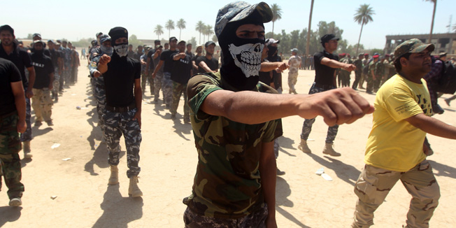 Shiite volunteers from the Iraqi Ketaeb (brigade) Hezbollah, march as they join the Iraqi army to fight against Jihadist militants of the Islamic State (IS), formerly known as the Islamic State in Iraq and the Levant (ISIL), on July 9, 2014, in Baghdad.. Iraq's government once battled entrenched Shiite militiamen but is now making common cause with them against a jihadist-led onslaught that Baghdad's forces are struggling to contain on their own. AFP PHOTO/AHMAD AL-RUBAYE