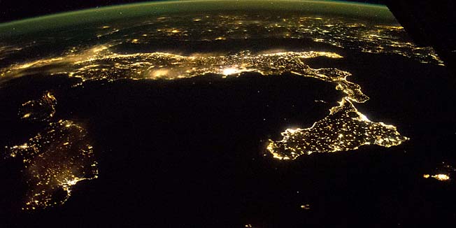 This image released by NASA December 15, 2014 shows the easily recognized boot of Italy, with Sicily at its toe, spread across this panorama taken October 21 by astronauts aboard the International Space Station(ISS). On a clear night looking east, the pattern of night lights shows populations concentrated mainly along the coastlines, but also in the Po River Valley of northern Italy(L). Some of the brightest clusters of lights are Rome and nearby Naples, with island cities of Cagliari on Sardinia and Catania on Sicilynow well-known as the hometown of European Space Agency astronaut Luca Parmitano. The small, dark, circular patch dangerously close to Catania marks the unpopulated slopes of the active volcano Etna. Hazy lights, as over the Po valley and Rome, probably indicate thin clouds above. The island of Malta appears at the lower right. The airglow line is vivid in this night shot. AFP PHOTO / HANDOUT / NASA   == RESTRICTED TO EDITORIAL USE / MANDATORY CREDIT: 