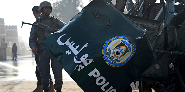 Afghan policemen stand guard alongside a damaged police ranger vehicle at the site of a remote-controlled bomb blast in Jalalabad on December 17, 2014.  Two remote-controlled bombs hit police vehicles around Jalalabad city in the east of Afghanistan, killing two police and wounding six others, Ahmad Zia Abdul Zai, the provincial spokesman said.  AFP PHOTO / Noorullah Shirzada