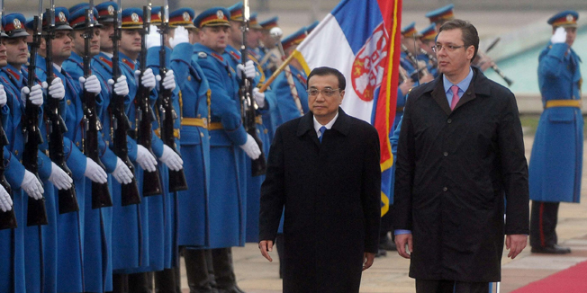 Chinese Prime Minister Li Keqiang (L) and his Serbian counterpart Aleksandar Vucic (R) inspect a guard of honor prior to their meeting in Belgrade on December 17, 2014. China signed a huge deal Wednesday to finance a high-speed bullet train between Budapest and Belgrade, a key link in Beijing's expanding network for getting its goods to European markets.    AFP PHOTO / ALEXA STANKOVIC