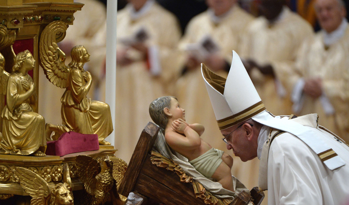Pope Francis kisses the unveiled baby Jesus during a Christmas Eve mass at St Peter's Basilica to mark the nativity of Jesus Christ, on December 24, 2014 at the Vatican. AFP PHOTO / ALBERTO PIZZOLI