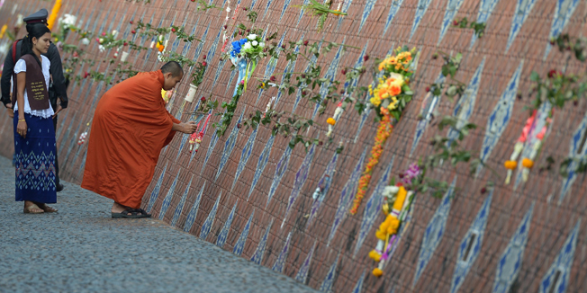 A Buddhist monk visits the Ban Nam Khem tsunami memorial park wall on the tenth anniversary of the 2004 tsunami in Phang-nga province on December 26, 2014.  Prayer recitals and solemn visits to mass graves marked the start of mourning on December 26 across tsunami-hit nations for the 220,000 people who perished when giant waves decimated coastal areas of the Indian Ocean a decade ago.  AFP PHOTO / Pornchai KITTIWONGSAKUL