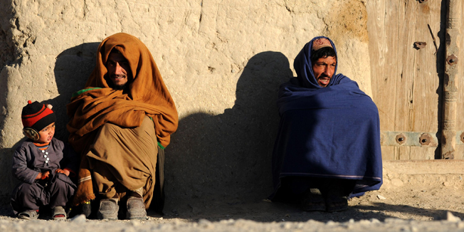 Afghan residents sit in front of their house in Kandahar on December 25, 2014.  Afghanistan's economy has improved significantly since the fall of the Taliban regime in 2001 largely because of the infusion of international assistance. Despite significant improvement in the last decade the country is still extremely poor and remains highly dependent on foreign aid.  AFP PHOTO/Javed Tanveer