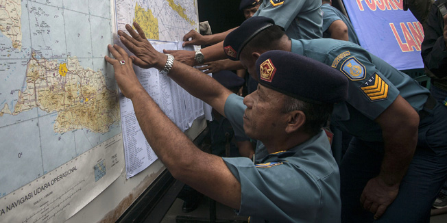 Indonesian Air Force officials show maps to journalists of the search area for the missing Malaysian air carrier AirAsia flight QZ8501, at the airport in Surabaya, East Java, on December 29, 2014. The AirAsia plane which went missing with 162 people on board en route for Singapore is likely at the bottom of the sea, Indonesia's National Search and Rescue Agency chief said on December 29. AFP PHOTO / Juni KRISWANTO