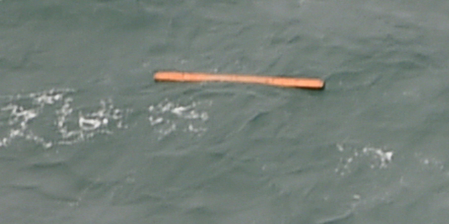 This aerial view taken from an Indonesian search and rescue aircraft over the Java Sea shows floating debris spotted in the same area as other items being investigated by Indonesian authorities as possible objects from missing AirAsia flight QZ8501 on December 30, 2014.  Items resembling an emergency slide, plane door and other objects were spotted during a aerial search on December 30 for the missing AirAsia plane, according to information from the flight on which AFP was aboard.    AFP PHOTO / Bay ISMOYO