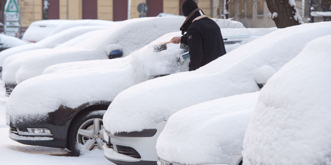 A man takes off snow from his car on December 29, 2014 in Berlin after an overnight snowfall.   AFP PHOTO / DPA / MAURIZIO GAMBARINI /GERMANY OUT