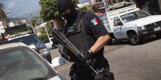ACAPULCO, MEXICO - MARCH 01:  A Mexican federal policeman inspects an abandoned car on March 1, 2012 in Acapulco, Mexico. Stolen vehicles used by drug gangs are often found abandoned throughout the city. Drug violence surged in the coastal resort last year, making Acapulco the second most deadly city in Mexico after Juarez. One of Mexico's top tourist destinations, Acapulco has suffered a drop in business, especially from foreign tourists, due to reports of the violence. Toursim accounts for some 9 percent of Mexico's economy and about 70 percent of the output of Acapulco's state of Guerrero.  (Photo by John Moore/Getty Images)
