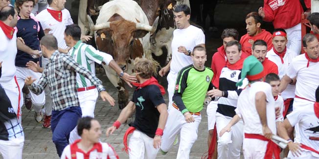 Participants run in front of Torrestrella's bulls during the first bull-run of the San Fermin Festival, on July 7, 2014, in Pamplona, northern Spain. The festival is a symbol of Spanish culture that attracts thousands of tourists to watch the bull runs despite heavy condemnation from animal rights groups. AFP PHOTO / RAFA RIVAS