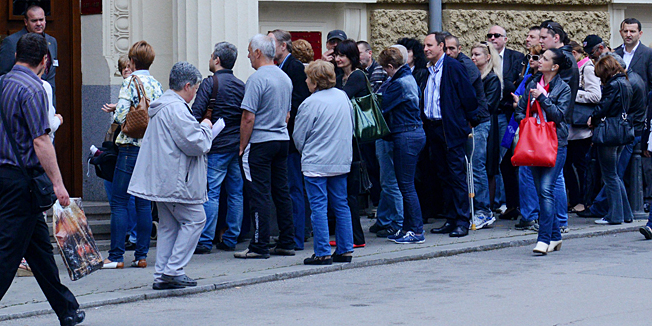 People stand in line in front of the main office of Bulgaria's Corporate Commercial Bank in Sofia on June 20, 2014. Dozens of worried Bulgarians were queueing outside the headquarters of the country's fourth-biggest private bank today after it filed for special insolvency protection from the EU member's central bank. The soundness of Bulgaria's banking sector is a sensitive issue, after a scare about the liquidity of a lender prompted a bank run in 1996-1997 causing 14 others to go bankrupt.   AFP PHOTO / JULIA LAZAROVA
