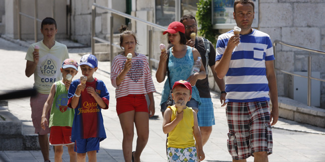Makarska, 140713.Vecina turista za vrijeme obilaska grada radije odlucuje za brzo osvjezenje uz sladoled s nogu nego daleko skuplju varijantu u kaficu ili restoranu.Na slici: Turisti uzivaju u sladoledu.Foto: Ivo Ravlic / CROPIX