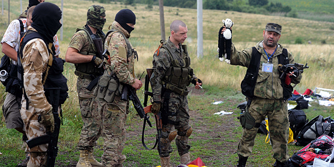 A pro-Russia militant holds up a stuffed animal as others look on at the site of the crash of a Malaysian airliner carrying 298 people from Amsterdam to Kuala Lumpur in Grabove, in rebel-held east Ukraine, on July 18, 2014. Pro-Russian separatists in the region and officials in Kiev blamed each other for the crash, after the plane was apparently hit by a surface-to-air missile. Members of the UN Security Council demanded a full, independent investigation into the apparent shooting down of a Malaysia Airlines jet over Ukraine.  AFP PHOTO / DOMINIQUE FAGET