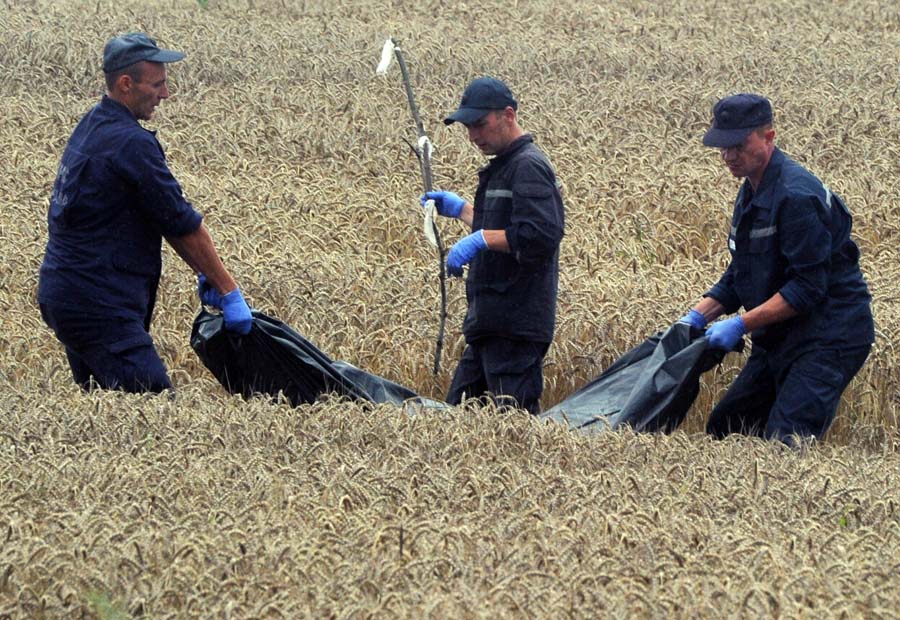 Ukrainian rescue workers collect the bodies of victims in a wheat field at the site of the crash of a Malaysia Airlines plane carrying 298 people from Amsterdam to Kuala Lumpur in Grabove, in rebel-held east Ukraine, on July 19, 2014. Ukraine and pro-Russian insurgents agreed on July 19 to set up a security zone around the crash site of a Malaysian jet whose downing in the rebel-held east has drawn global condemnation of the Kremlin. Outraged world leaders have demanded Russia's immediate cooperation in a prompt and independent probe into the shooting down on July 17 of flight MH17 with 298 people on board. AFP PHOTO / DOMINIQUE FAGET