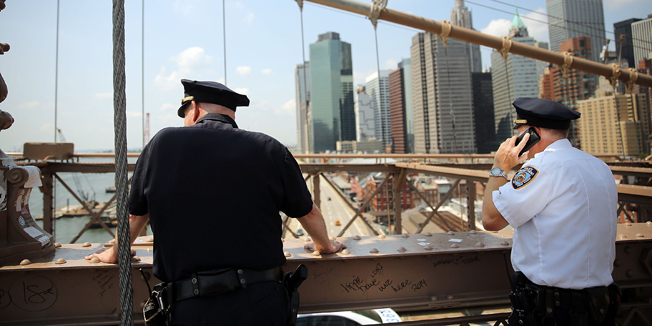 NEW YORK, NY - JULY 22: Police stop along the Brooklyn Bridge following the discovery of a pair of white flags that appeared overnight atop the two towers of the Brooklyn Bridge replacing the American flags on July 22, 2014 in New York City. Police are investigating the incident which turned one of New York's iconic pieces of architecture into a police investigation scene as hundreds of curious people looked on.   Spencer Platt/Getty Images/AFP== FOR NEWSPAPERS, INTERNET, TELCOS & TELEVISION USE ONLY ==