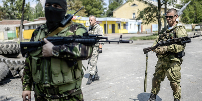 Pro-Russia separatists stand at their checkpoint near the front line in the northern outskirts of city of Donetsk, on July 22, 2014. Terrified civilians fled as intense clashes yesterday between Ukrainian government troops and pro-Russian rebels left at least four people dead on the outskirts of the insurgent bastion of Donetsk. A military spokesman said yesterday government troops were battling back control of the districts around the airport and had broken through the rebel cordon to reach their comrades inside.  AFP PHOTO/ BULENT KILIC