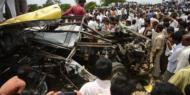 Indian bystanders are pictured gathered around the mangled wreckage of a school bus at the scene of the collision between a school bus and a train at Thoopran Mandal of Medak District, about 58 kilometers from Hyderabad, on July 24, 2014.  A passenger train rammed into a school bus in southern India, killing at least 11 children, with fears the death toll could be as high as 25, officials said.   AFP PHOTO/NOAH SEELAM
