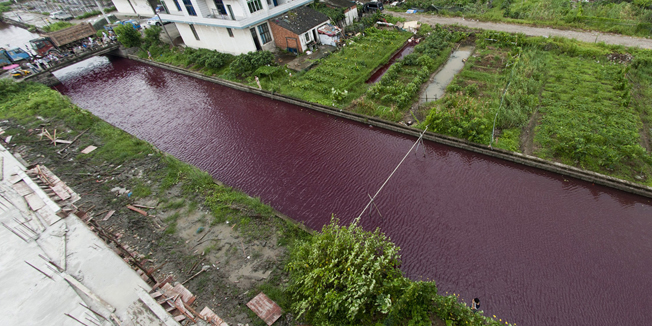 This picture taken on July 24, 2014 shows a river with its water turned to red in Wenzhou, east China's Zhejiang province.  Residents said the river looked normal at five in the morning but was blood red within an hour on July 24, local media reported.     CHINA OUT   AFP PHOTO