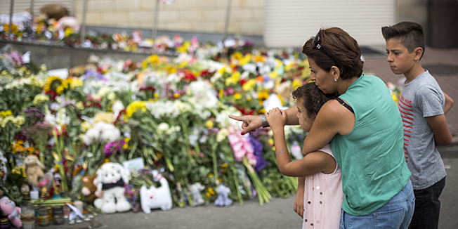 KIEV, UKRAINE - JULY 19:  A mother and her two children look at candles and flowers left in front of the Netherlands Embassy in memory of the victims of Malaysia Airlines flight MH17 on July 19, 2014 in Kiev, Ukraine. Malaysia Airlines flight MH17 was travelling from Amsterdam to Kuala Lumpur when it crashed killing all 298 on board including 80 children. The aircraft was allegedly shot down by a missile and investigations continue over the perpetrators of the attack.  (Photo by Rob Stothard/Getty Images)