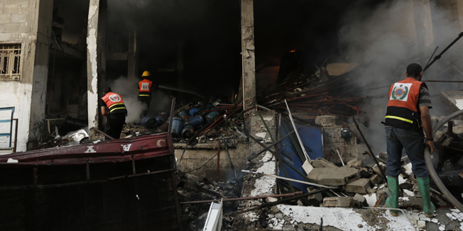 Firefighters battle a building on fire after several strikes early on July 29, 2014.  Five Israeli soldiers died in clashes with a Palestinian commando that tried to reach Israel through a tunnel at Nahal Oz, near the border with Gaza, the army said. AFP PHOTO / MOHAMMED ABED