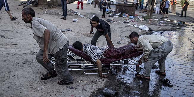 Palestinian men move the victim of an Israeli air strike on a market place to an ambulance in the Shejaiya neighbourhood near Gaza City on July 30, 2014. At least 17 people were killed and 150 people wounded, medics said.The strike came shortly after the Israeli army said it was observing a humanitarian lull that would be in force for four hours from 1200 GMT. AFP PHOTO/MARCO LONGARI