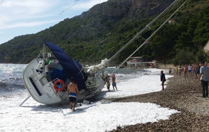 Komiza, 300714. Veliki valovi otrgnuli su talijansku jedrilicu s njenog veza udaljenog 200-tinjak metara od plaze na kojoj se nasukala. Na jedrilici dugackoj 10 metara nije bilo ljudi a na plazi na kojoj se nasukala nitko od kupaca nije ozlijedjen. Foto: Marijan Bukovec / CROPIX