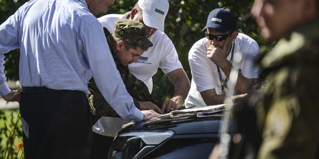 Deputy Chief Monitor of the Organization for Security and Cooperation in Europe (OSCE) Special Monitoring Mission to Ukraine, Alexander Hug (L), and other OSCE members read a map with a separatist (2nd L) in Donetsk on July 30, 2014. Ukraine's army on July 28 seized control of part of the vast site where Malaysian airliner MH17 crashed, pro-Russia rebels , as the United Nations announced the downing of the plane could constitute a war crime. Observers from the Organisation for Security and Co-operation in Europe were set to arrive in southern Russia on July 30 on their mission to monitor two border crossings with rebel-held Ukraine. AFP PHOTO/ BULENT KILIC