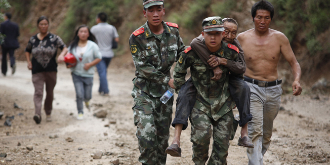 Chinese rescuers carry an injuried resident after an earthquake hit an area of Ludian county in Zhaotong in southwest China's Yunnan province on August 3, 2014. At least 150 people were killed and 1,300 injured after a strong earthquake hit southwest China's mountainous Yunnan province, state media said. The quake in Zhaotong prefecture, in the province's northeast, toppled buildings and left residents frantically searching for survivors beneath the rubble, images on social media showed.  AFP PHOTO/STR  CHINA OUT