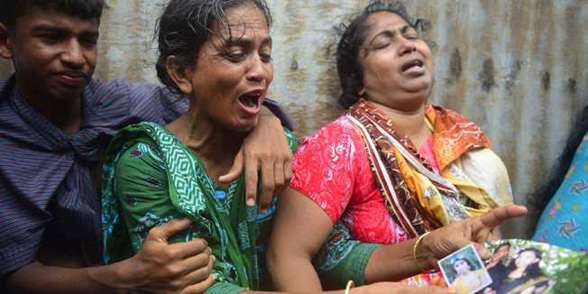 Bangladeshis, holding photographs of their loved ones, mourn for their missing relatives after an overloaded ferry capsized in the Padma river in Munshiganj, some 30 kilometres (20 miles) south of the capital Dhaka, on August 4, 2014. An overloaded ferry carrying up to 200 passengers sank August 4 on a river in central Bangladesh, police said. AFP PHOTO/Munir uz ZAMAN