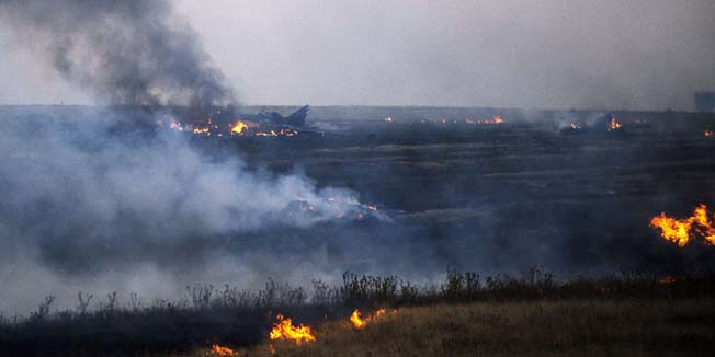 Smoke billows from the flaming debris of a crashed Ukrainian fighter jet near the village of Zhdanivka, some 40 kilometres northeast of the rebel stronghold of Donetsk, eastern Ukraine, on August 7, 2014. A Ukranian fighter jet tumbled to earth in a fireball after it was blasted out of the air while flying low over rebel-held territory in the east of the country. An AFP crew saw the Sukhoi warplane explode in mid-air and the parachute of at least one pilot opening up in the clear blue sky. AFP PHOTO / DIMITAR DILKOFF