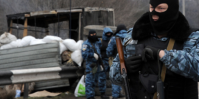 Armed masked men who call  themselves members of Ukraine's disbanded elite Berkut riot police force stand at their checkpoint under a Russian flag on a highway that connect Black Sea Crimea  peninsula to mainland Ukraine near the city of Armyansk, on February 28, 2014. The spiralling tensions in a nation torn between the West and Russia took today a severe new turn when Ukraine's interim president Oleksandr Turchynov accused Russian soldiers and local pro-Kremlin militia of staging raids on Crimea's main airport and another base on the southwest of the peninsula where pro-Moscow sentiments run high. AFP PHOTO / VIKTOR DRACHEV