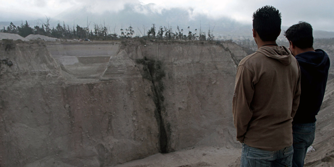 Two men stare at the Catequilla mine, near Quito, following a landslide after a 5.1-magnitude earthquake rattled the Ecuadoran capital and the surrounding area causing buildings and homes to shake violently, on August 12, 2014. The quake triggered landslides that killed at least two people and left three others trapped while another eight people were also injured at quarries on the outskirts of Quito.    AFP PHOTO/JUAN CEVALLOS