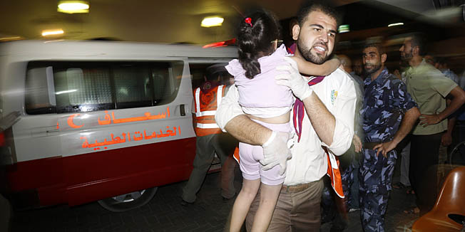A Palestinian doctor carries a wounded child  at the hospital following an Israeli air strike on a house in Gaza City on August 19, 2014. The Israeli air strike killed a young girl and a woman, wounding 16 other people. Israel carried out a series of air strikes across the Gaza Strip in response to a string of Palestinian rocket attacks on southern Israel that torpedoed a 24-hour ceasefire meant to hold until 2100 GMT. AFP PHOTO / MOHAMMED ABED