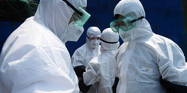 This picture taken on August 19, 2014 shows quarantine officers inspecting the Alpha Friendship, a bulk carrier registered in Greece that carries ores from the Pepel port in Sierra Leone, one of the Ebola-hit area in Western Africa, as the ship berths in the quarantine anchorage waiting for its entry in the port at Qingdao, in eastern China's Shandong province.  Ebola has killed more than 1,220 people since it emerged in southern Guinea at the start of the year, spreading first to Liberia and cutting a gruesome and gory swathe through eastern Sierra Leone since May.     CHINA OUT   AFP PHOTO