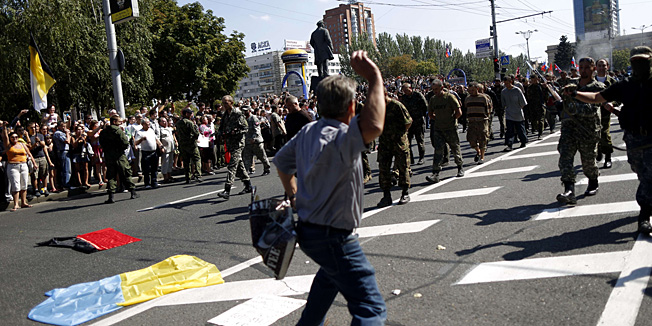 TOPSHOTSA man throws a projectile and people watch as captured Ukrainian soldiers walk on Lenin square on August 24, 2014 in Donetsk, eastern Ukraine, during a parade in mockery of the country's Independence Day celebrations. Pro-Russian rebels in eastern Ukraine paraded dozens of captured soldiers before a jeering crowd on August 24 in a bid to mock Kiev's Independence Day celebrations. In the capital, the Ukrainian government had sought to boost morale and send a defiant message to the rebels with an upbeat military parade to mark the country's independence from the Soviet Union in 1991. AFP PHOTO / MAX VETROV