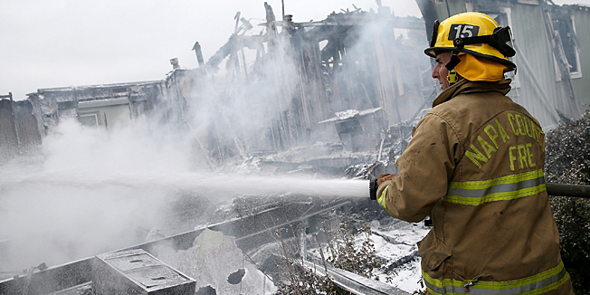 NAPA, CA - AUGUST 24: A Napa County firefighter sprays foam on hot spots from a fire at a mobile home park following a reported 6.0 earthquake on August 24, 2014 in Napa, California. A 6.0 earthquake rocked the San Francisco Bay Area shortly after 3:00 am on Sunday morning causing damage to buildings and sending at least 70 people to a hospital with non-life threatening injuries.   Justin Sullivan/Getty Images/AFP== FOR NEWSPAPERS, INTERNET, TELCOS & TELEVISION USE ONLY ==