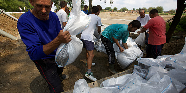 Rajevo Selo, 080714.Zbog velikih kisa koje su dovele do rasta vodostaja Save u Rajevom Selu je zapocela izgradnja zastitnog nasipa.Mjestani i radnici na javnim radovima postavljaju vrece s pijeskom na privremeni nasip ispred starog nasipa koji je pukao priilikom nedavne poplave i jos uvijek nije saniran.Na fotografiji: radnici pune vrece s pijeskom za nasip.Foto: Vlado Kos / Cropix
