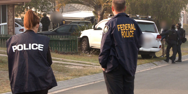 A handout photo from the Australian Federal Police taken and received on September 10, 2014 shows Australian Federal Police officers arresting two suspect after raiding an Islamic centre in Brisbane and seizing two men for alleged involvement in recruiting and sending jihadist fighters to Syria.  The raids involving 180 police came a day after the country's spy chief said he was 