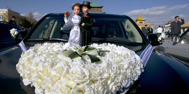 ULAANBATAAR, MONGOLIA - OCTOBER 18: A bride and groom are seen on top of a limousine at the Gandan Monastery on a special day on the Lunar calendar for wedding ceremonies October 18, 2012 Ulaanbataar, Mongolia. Mongolia has been undergoing massive social, economic and political changes since gaining independence from China some 100 years ago, and removing itself from the Soviet Bloc more than 20 years ago. The Oyu Tolgoi copper and gold mine is Mongolia's biggest foreign investment project to date adding an estimated 35% value to the country's GDP. (Photo by Paula Bronstein/Getty Images)