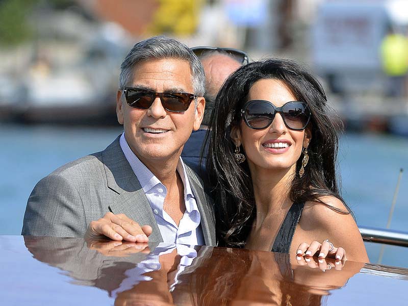 US actor George Clooney ( L) and his Lebanon-born British fiancee Amal Alamuddin take a taxiboat upon their arrival in Venice on September 26, 2014, on the eve of their wedding.    AFP PHOTO / ANDREAS SOLARO