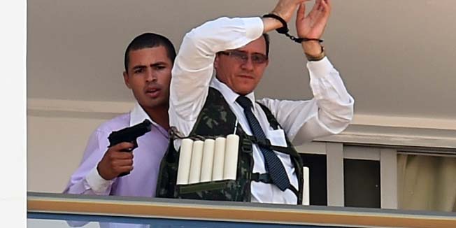 An unidentified man keeps a hotel employee with an explosive-laden vest at a balcony of the hotel in Brasilia on September 29, 2014. AFP PHOTO/EVARISTO SA