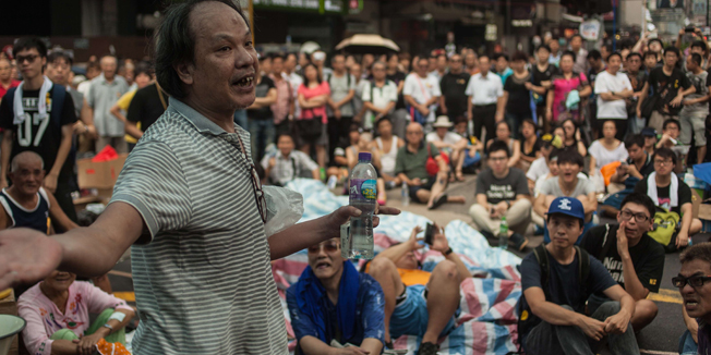 A pro Hong Kong government protestor (L) speaks to a crowd of pro-democracy activists in the Kowloon district of Hong Kong on September 30, 2014. Hong Kong has been plunged into the worst political crisis since its 1997 handover as pro-democracy activists take over the streets following China's refusal to grant citizens full universal suffrage. AFP PHOTO / ANTHONY WALLACE