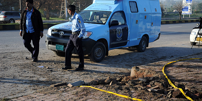 Pakistani policemen inspect the site of a bomb explosion in Islamabad on April 3, 2014. Pakistan's former military ruler Pervez Musharraf, who is on trial for treason, escaped the bomb blast in the early hours of April 3, police said.  AFP PHOTO/Aamir QURESHI