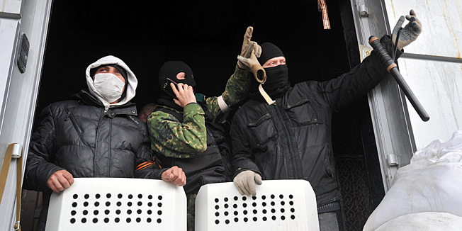 Pro-Russian activists gesture as they guard the entrance of the regional Security Service building in the eastern Ukrainian city of Lugansk on April 9, 2014.Ukraine said on Paril 9 that pro-Russian militants had freed 56 