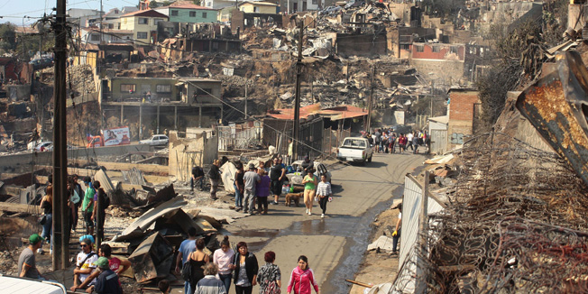 View of part of a neighborhood  destroyed by a blaze overnight,  in Valparaiso, Chile, on April 13, 2014. At least eleven people have died in a huge fire in Chile's port city of Valparaiso famous for its UNESCO-listed historic center, officials said Sunday. The blaze, which started in woodland near the city on Saturday and whose cause is under investigation, destroyed 500 homes and forced the evacuation of more than 5,000. AFP PHOTO/FELIPE GAMBOA