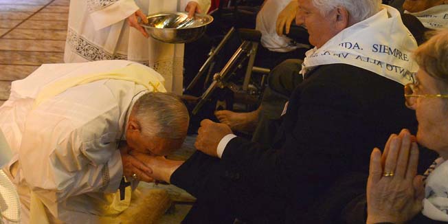 Pope Francis (L) kisses the foot of a man as he performs the traditional Washing of the feet during a visit at a center for disabled people as part of  Holy Thursday (Maundy Thursday) as part of the Holy Week on April 17, 2014 in Rome.  AFP PHOTO / ALBERTO PIZZOLI