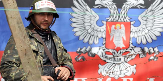 A pro-Russia activist stands guard in front of the flag of the so-called  Donetsk republic outside the police regional building seized by the separatists in the eastern Ukrainian city of Slavyansk on April 17, 2014. Russian President Vladimir Putin on Thursday said he very much hopes that he will not have to use his 