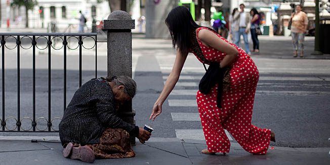 MADRID, SPAIN - JUNE 09:  A woman gives alms to a homeless in Cibeles Square on June 9, 2012 in Madrid, Spain. Despite the severe budget cuts that Spanish Government is making, Spanish prime minister Mariano Rajoy may have to agree this weekend a bailout to prevent collapse, that could bring a chain reaction, followed by Italy and destroy the Euro. The final figure of the size of the rescue package would be ready within a week.  (Photo by Pablo Blazquez Dominguez/Getty Images)